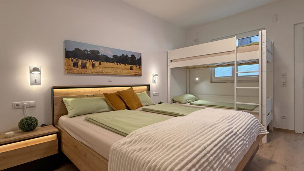 Helles Schlafzimmer mit Doppelbett, Etagenbett und Landschaftsbild an der Wand