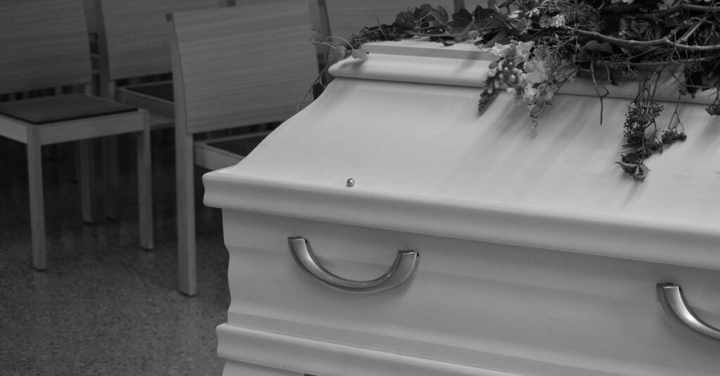 Sarg mit Blumenkranz im Raum